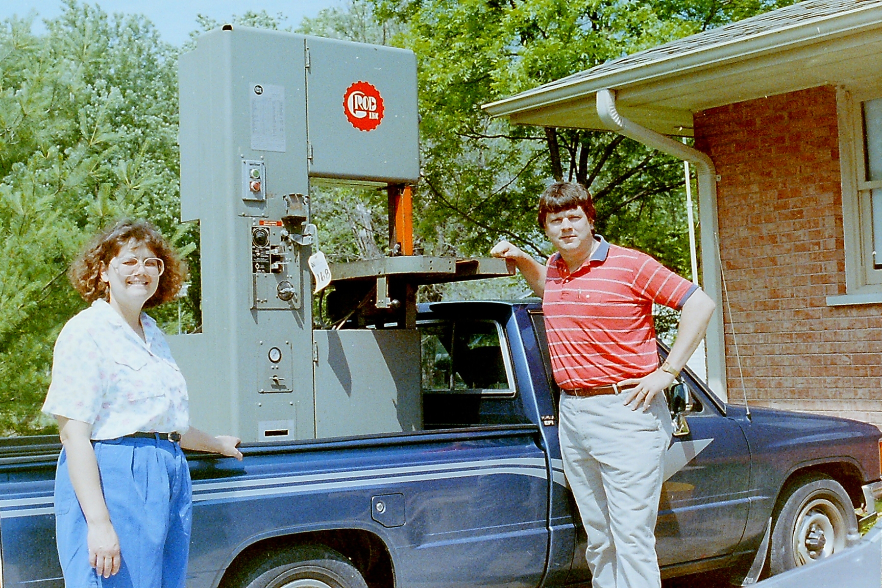 Young Bob and Judy Burns standing in front of a truck, their first machine in the bed.